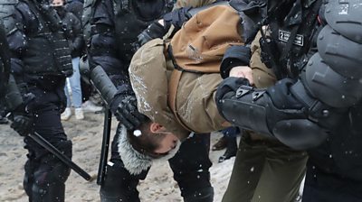 Protester held by police officers