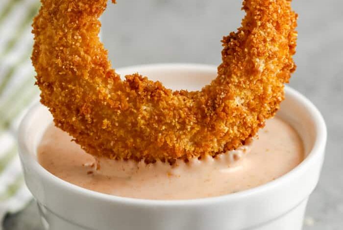 dipping and onion ring into Onion Ring Sauce