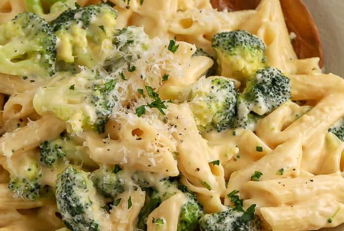 broccoli pasta on a white plate with a wooden spoon