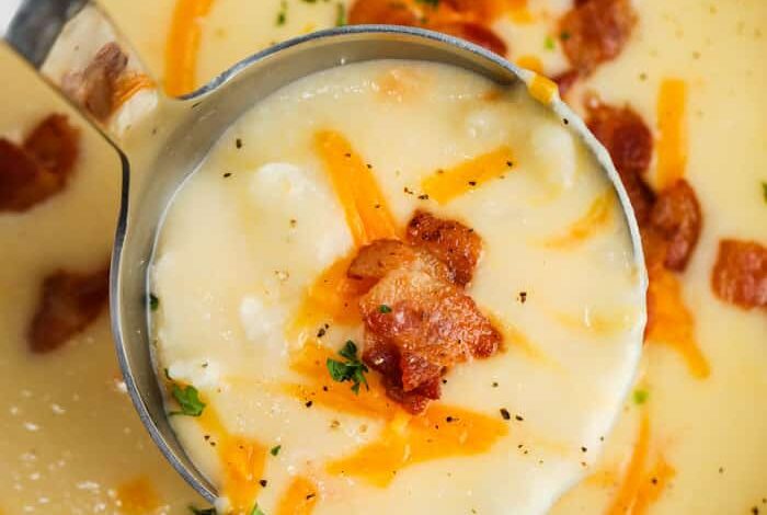 Cauliflower Cheddar Soup in the pot with a paddle full