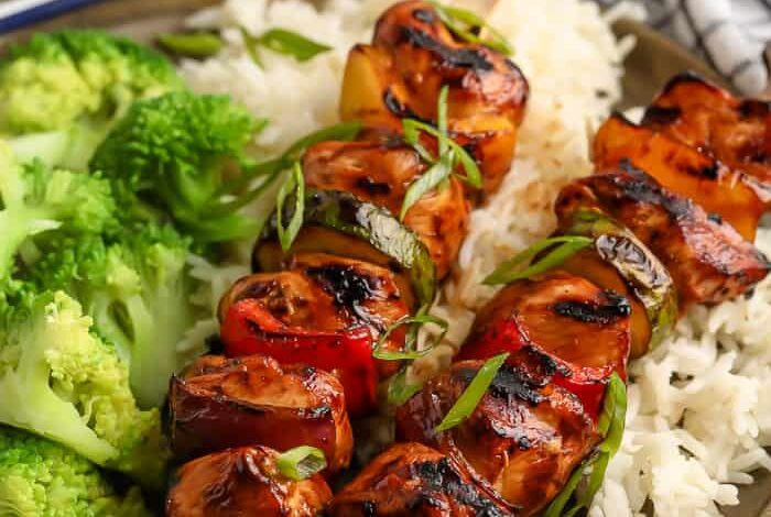 teriyaki chicken kabobs on a bed of rice with steamed broccoli