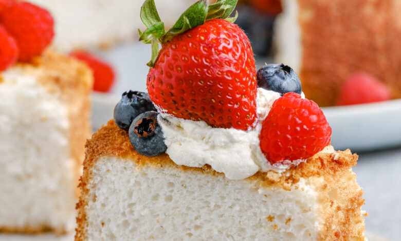 slice of Angel Food Cake on a plate with fresh fruit and whipped cream