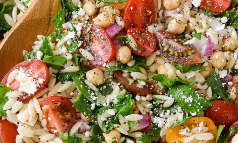 serving orzo pasta salad with a wooden spoon