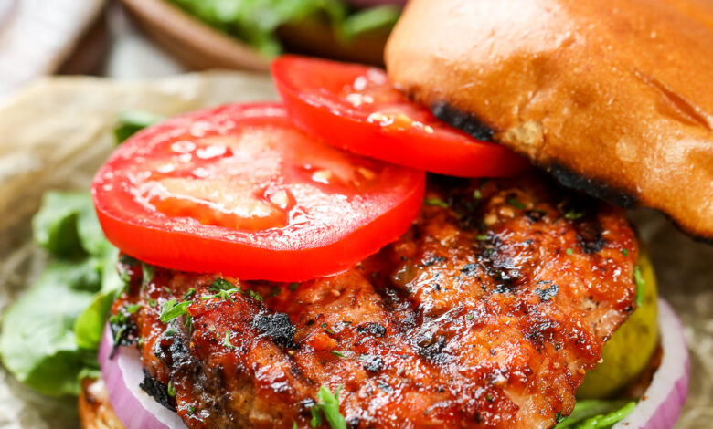 cooked turkey burger on a hamburger bun with tomatoes on top