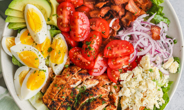 top view of Cobb Salad on a plate with ingredients and dressing around it