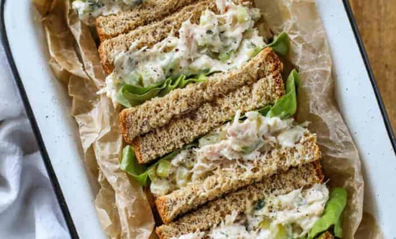 tuna sandwiches cut in half in a tin with lettuce