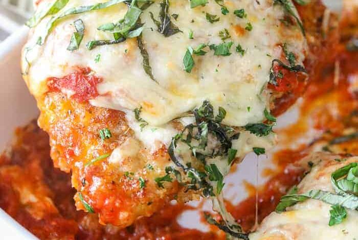 Classic Chicken Parmesan topped with fresh basil being served out of a baking dish