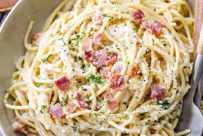 Spaghetti carbonara in a bowl with a fork and spoon