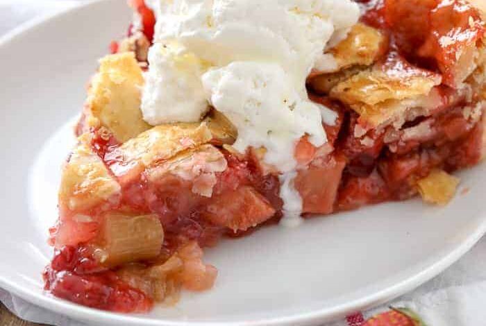 Strawberry Rhubarb Pie on a white plate with vanilla ice cream on top