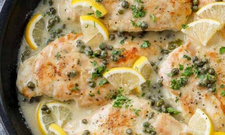 a skillet of chicken piccata garnished with lemon slices