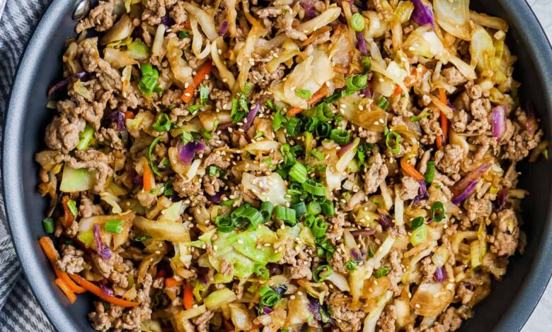 a skillet of egg roll in a bowl garnished with green onions and sesame seeds