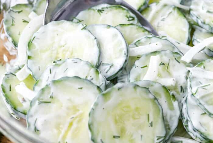 Creamy Cucumber Salad in a mixing bowl being stirred with a spoon