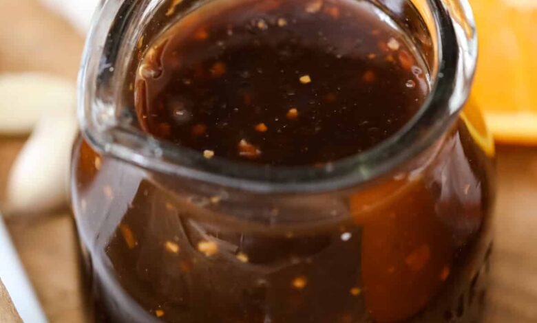 a jar of teriyaki sauce next to orange slices and garlic