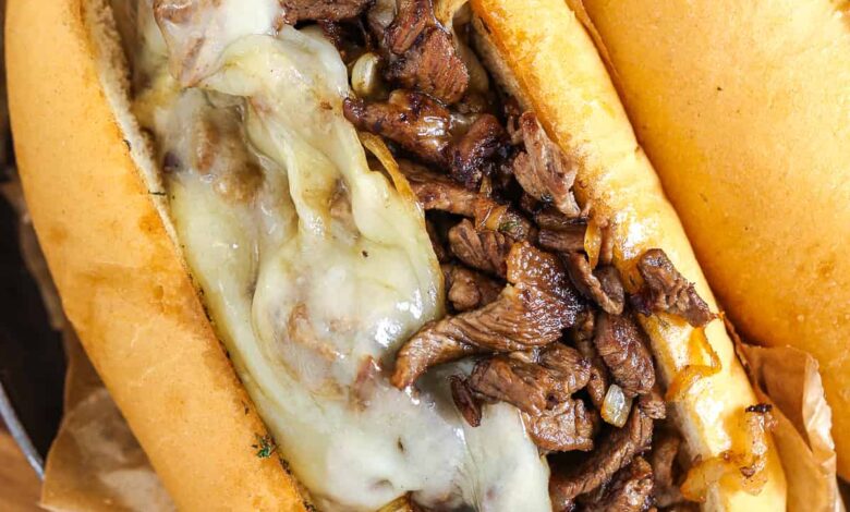 philly cheesesteak topped with cheese in a roll
