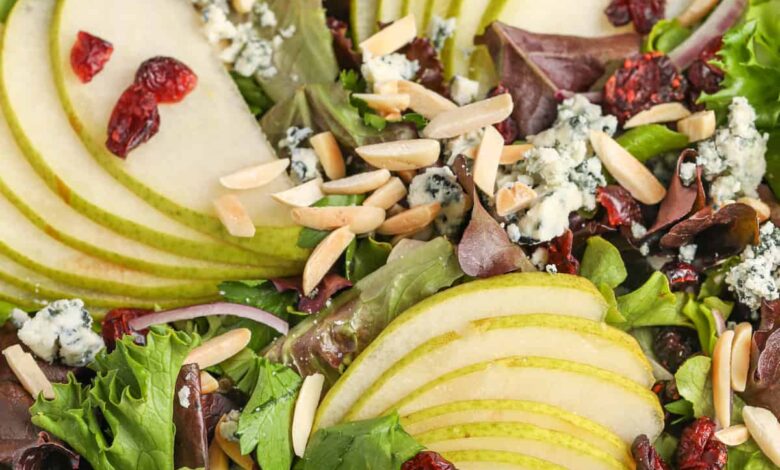 a pear salad topped with cranberries, almonds, and blue cheese