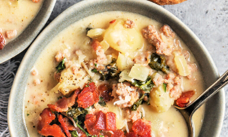 a bowl of zuppa toscana topped with bacon next to a baguette