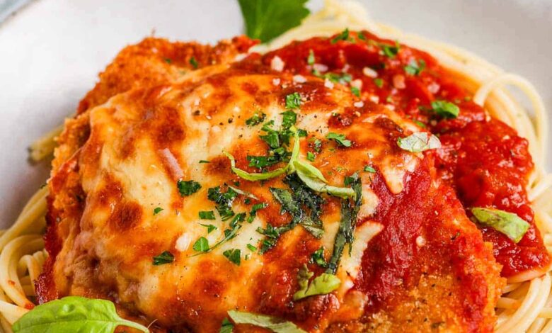 a bowl of spaghetti topped with baked chicken parmesan