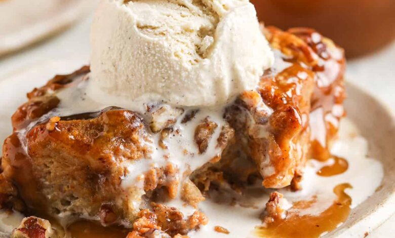 piece of pumpkin bread pudding on a plate with a bite taken out and a scoop of ice cream