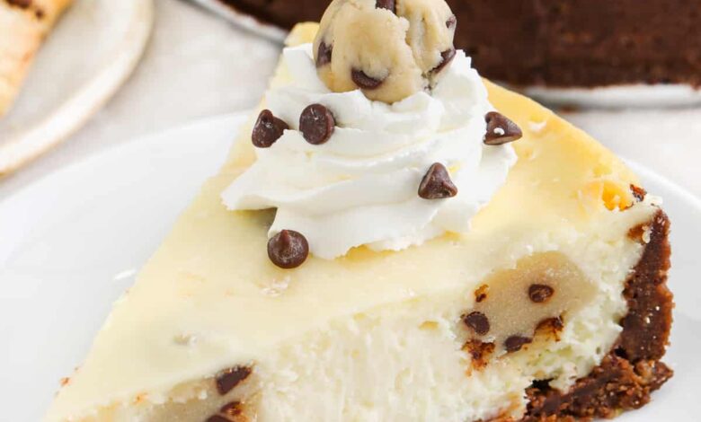 slice of Cookie Dough Cheesecake with full cheesecake in the back