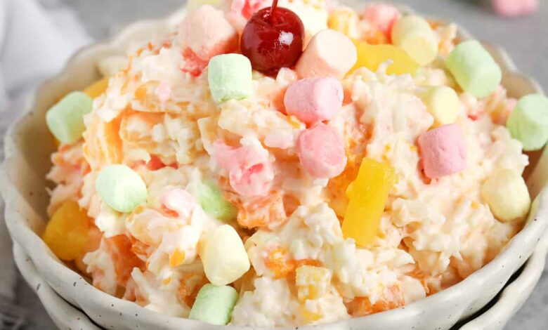 ambrosia salad in a bowl topped with a cherry