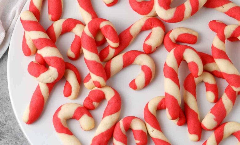 scattered baked candy cane cookies on a white plate