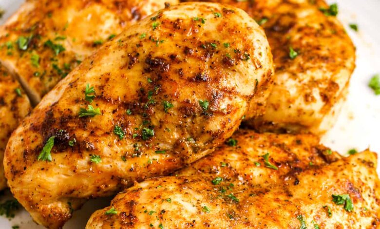 4 air fryer chicken breasts on a plate with green beans in the background