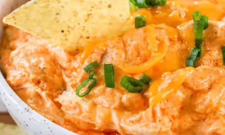 dipping a tortilla chip in Crockpot Buffalo Chicken Dip